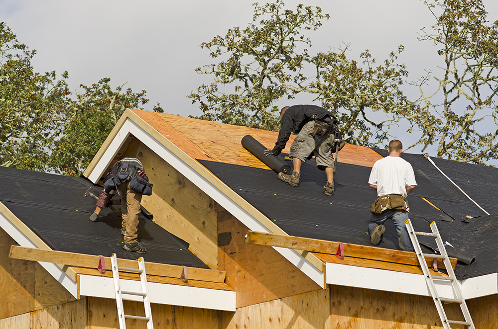 Construction crew working on the roof sheeting of a new, luxury residential home project 