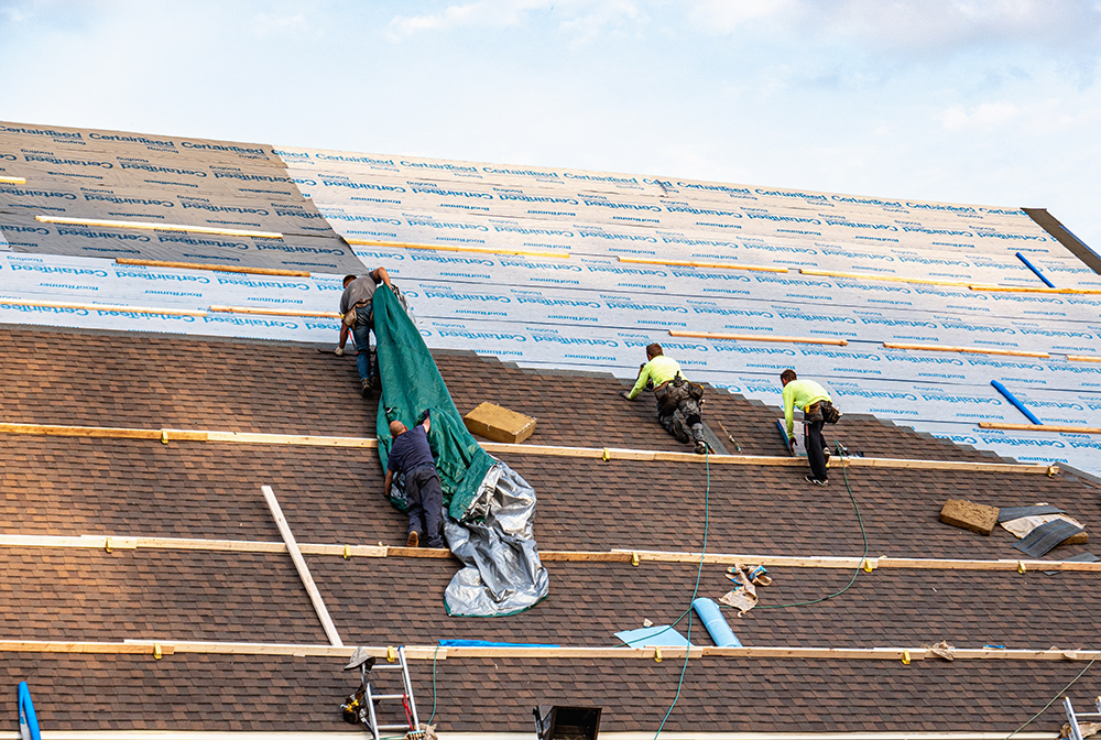 roofers at work installing peel and stick roof underlayment on a residential roofing system
