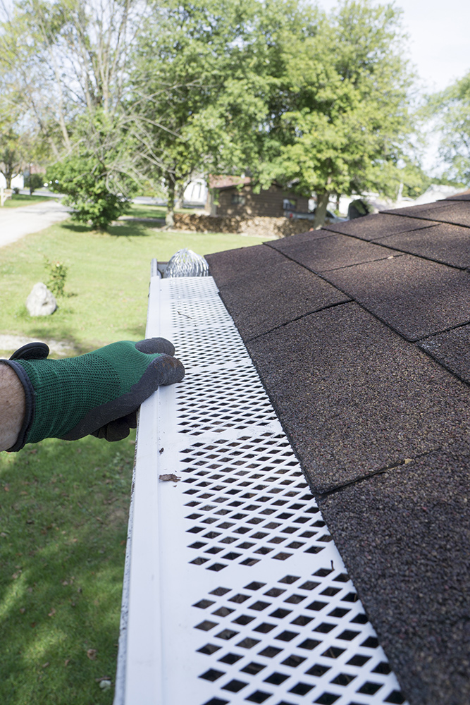 Contractor checking installation of plastic leaf guards on a screen gutter guard